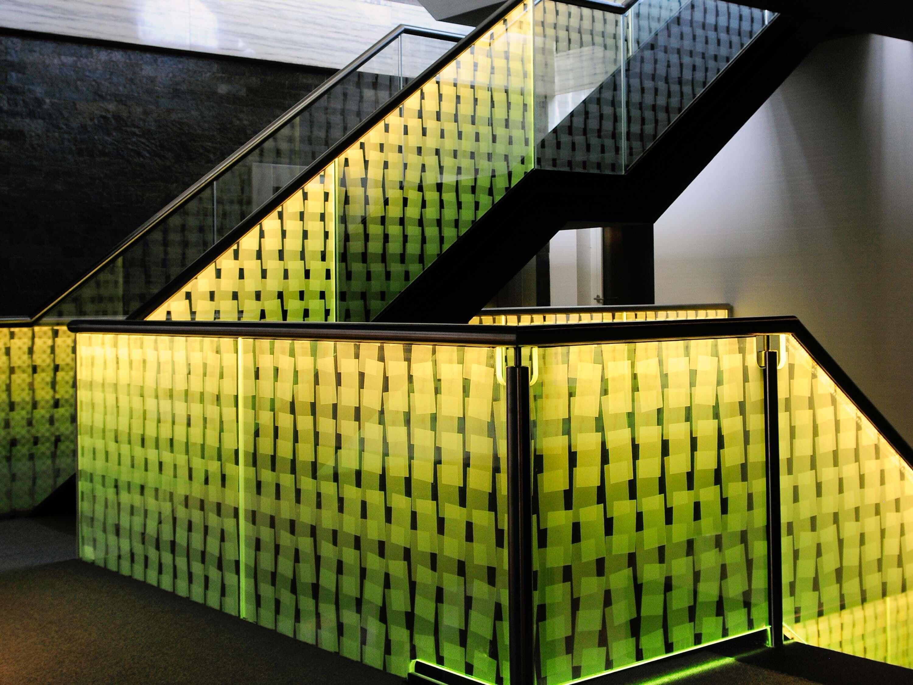 A staircase with glass railings and a patterned wall.