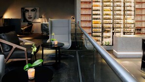 Ein modernes Interieur mit einer Sitzecke, einer Glaskonsole mit Weinflaschen und einem Marmor-Rezeptionsschalter.
