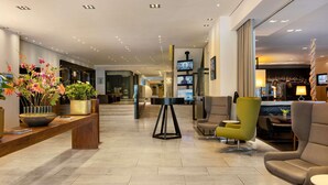 Eine Hotelhalle mit Empfangstresen, Sitzbereich und Bar.