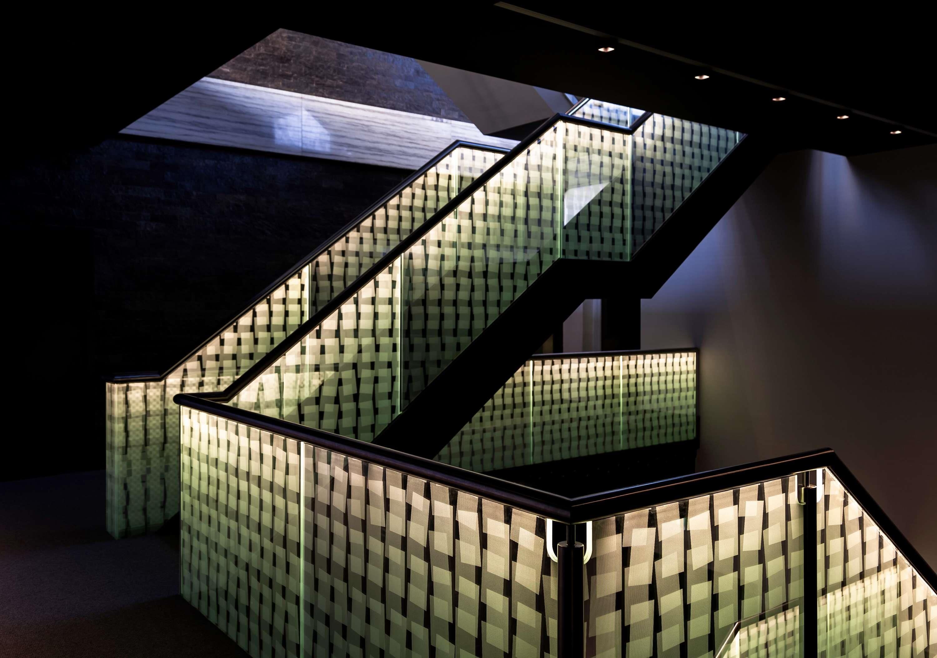 Un escalier à motifs à carreaux et une rampe en verre.