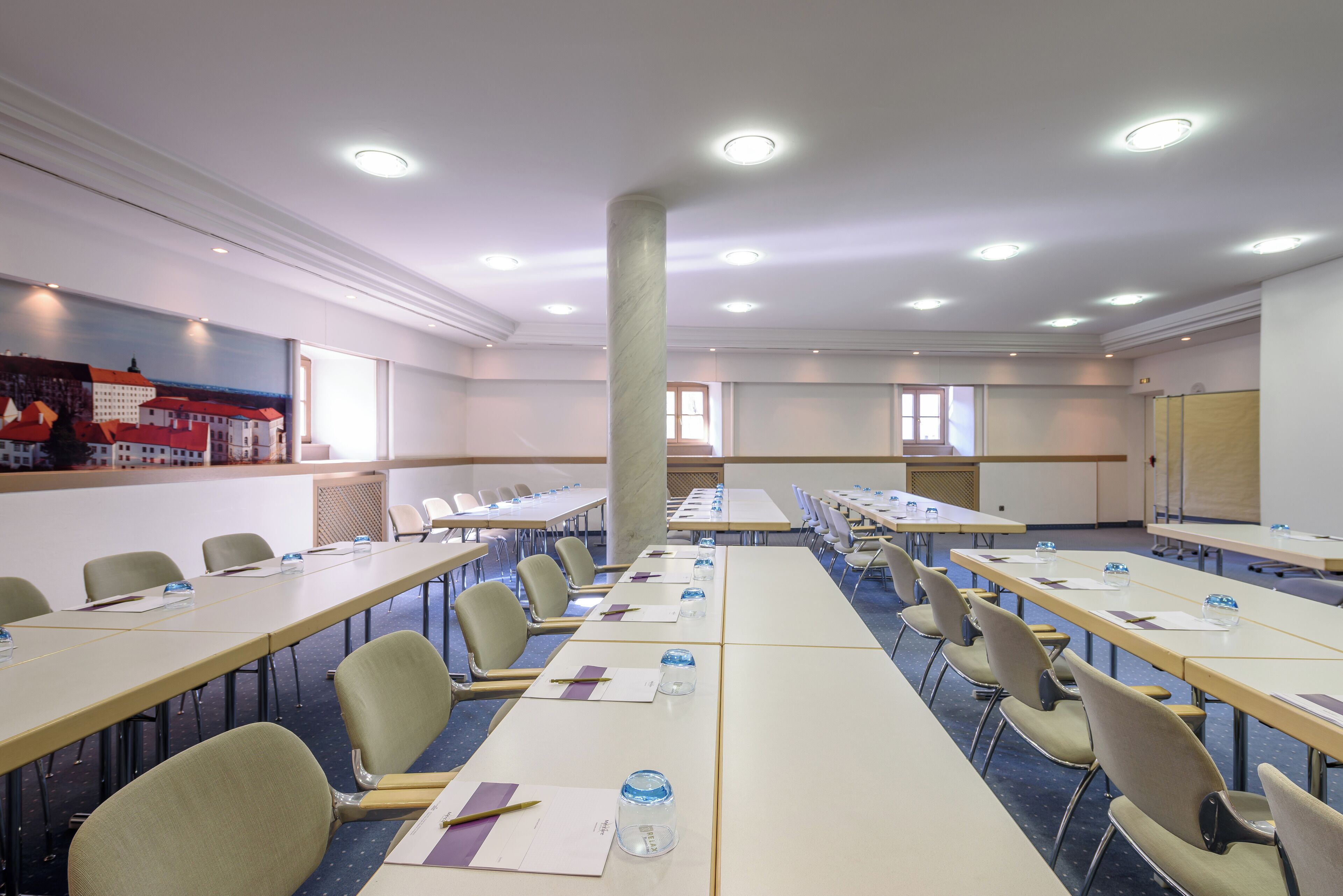 A conference room with long tables, chairs, and a large pillar.