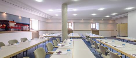 A conference room with long tables, chairs, and a large pillar.