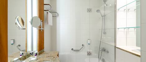 A modern bathroom with a granite countertop, a white sink, a large mirror, a glass-enclosed shower, and a glass shower door.