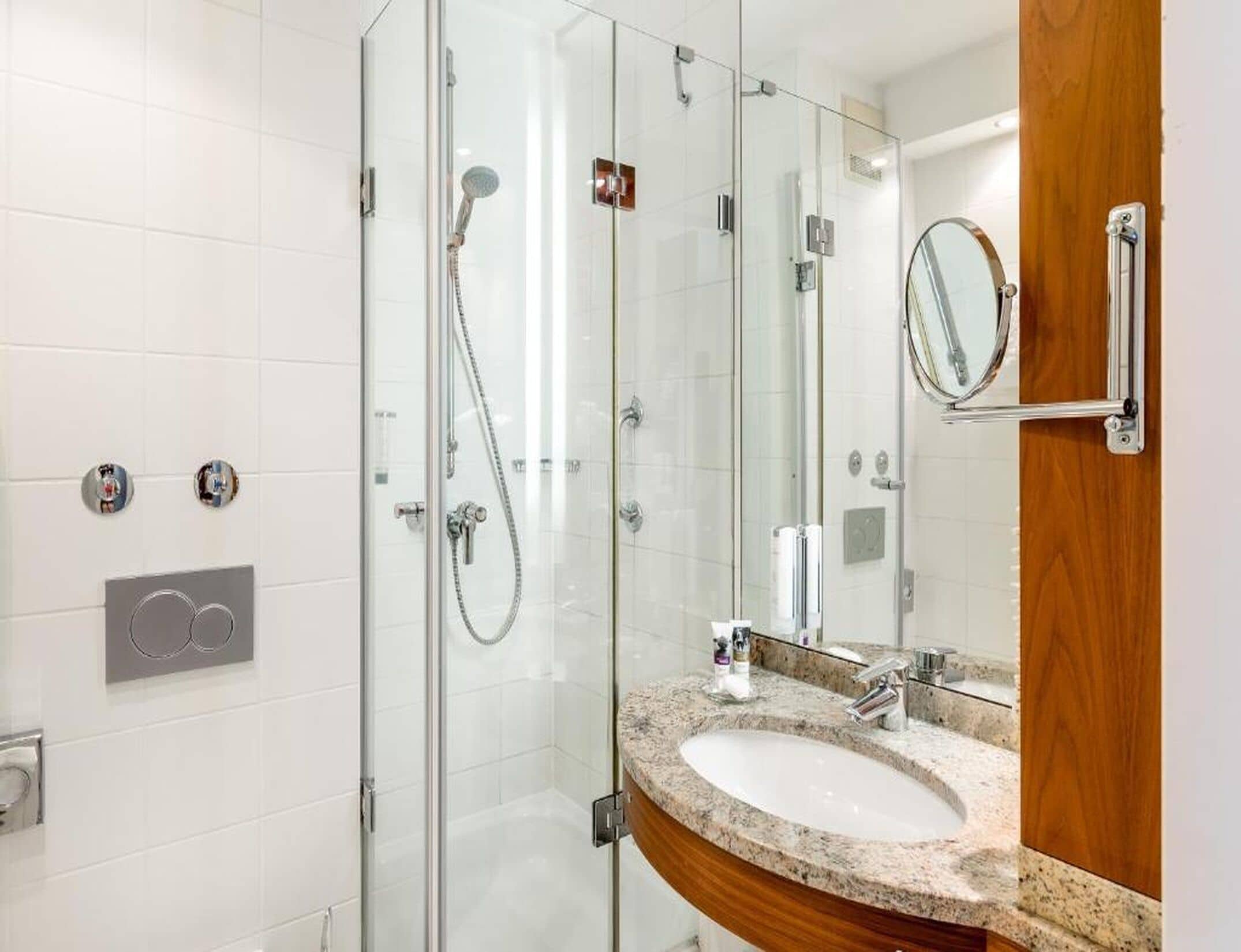 Une salle de bain moderne avec une douche à parois de verre, un lavabo en marbre et un meuble-lavabo en bois.