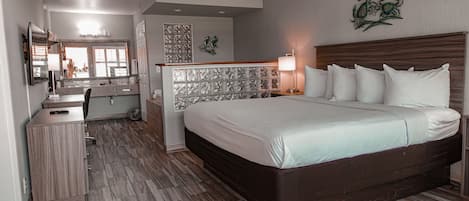 A hotel room with a large bed, a desk, a mirror, and a bathroom.