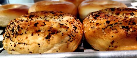 A tray of freshly baked bread rolls with sesame seeds on a metal rack.