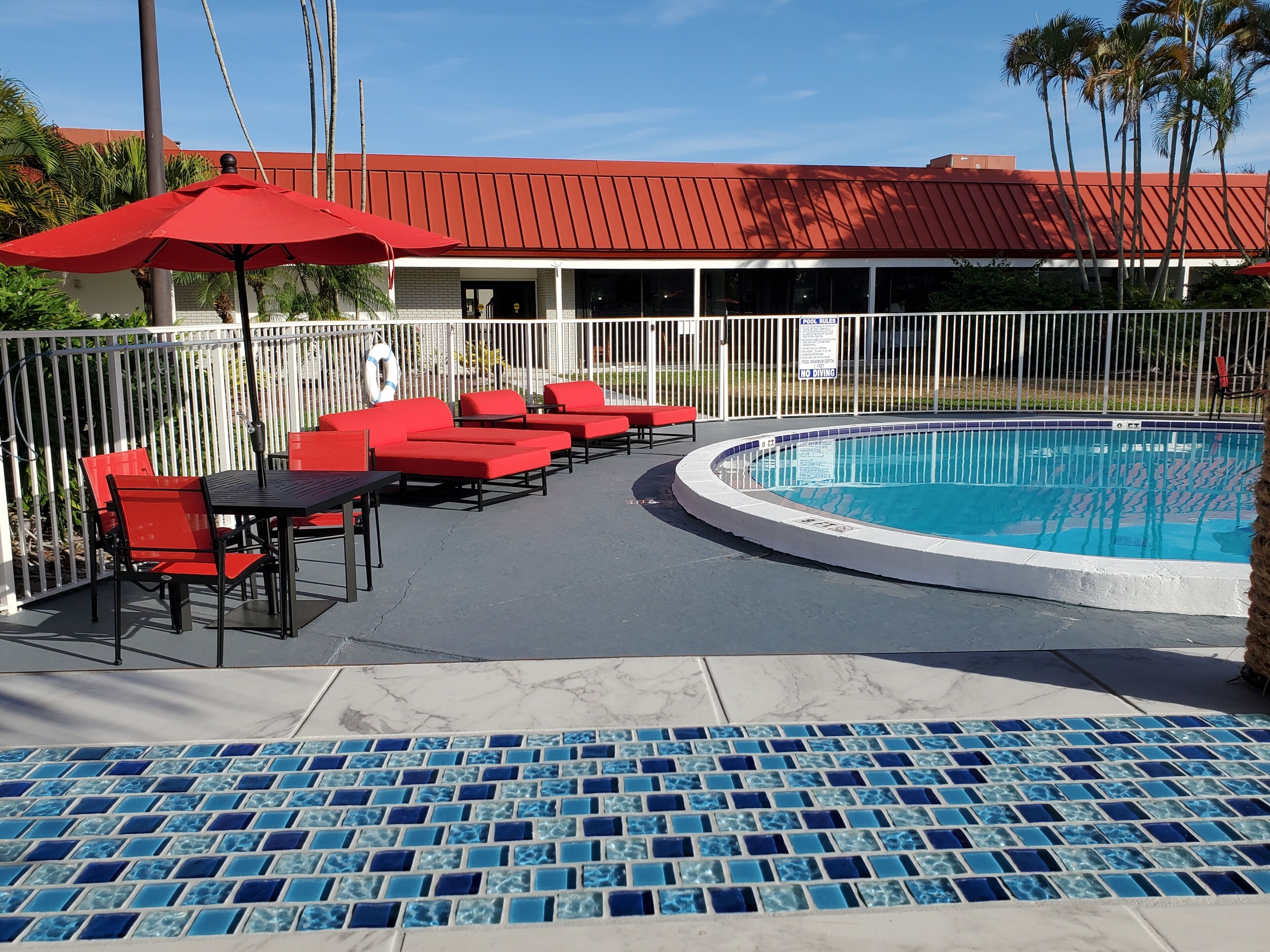 Zona de piscina con sillas reclinables rojas y una pileta.