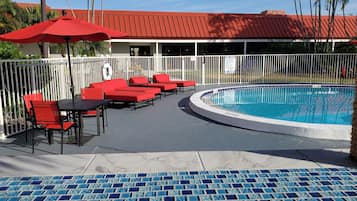 Zona de piscina con sillas reclinables rojas y una pileta.