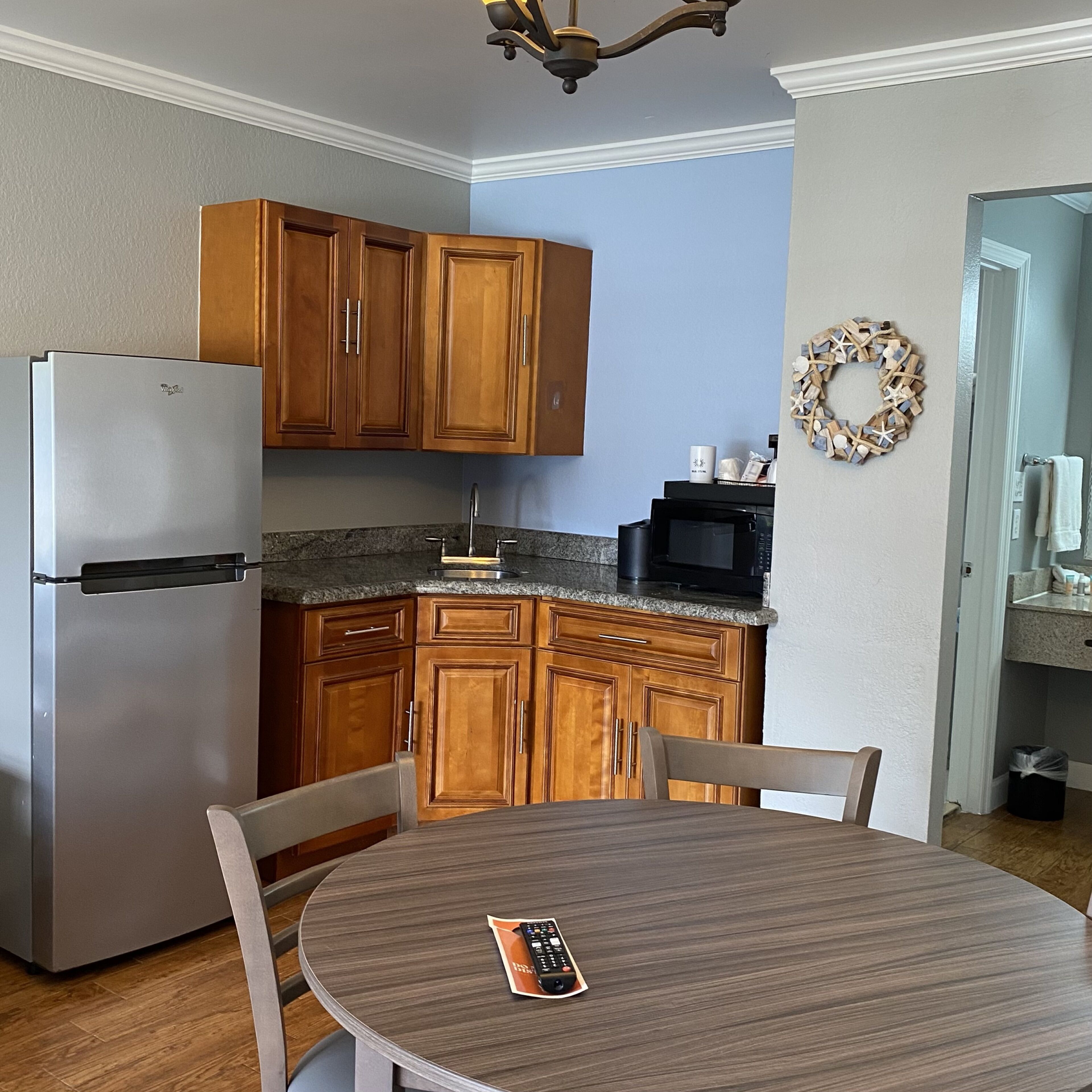 A kitchen with wooden cabinets, a refrigerator, a microwave, and a dining table with chairs.