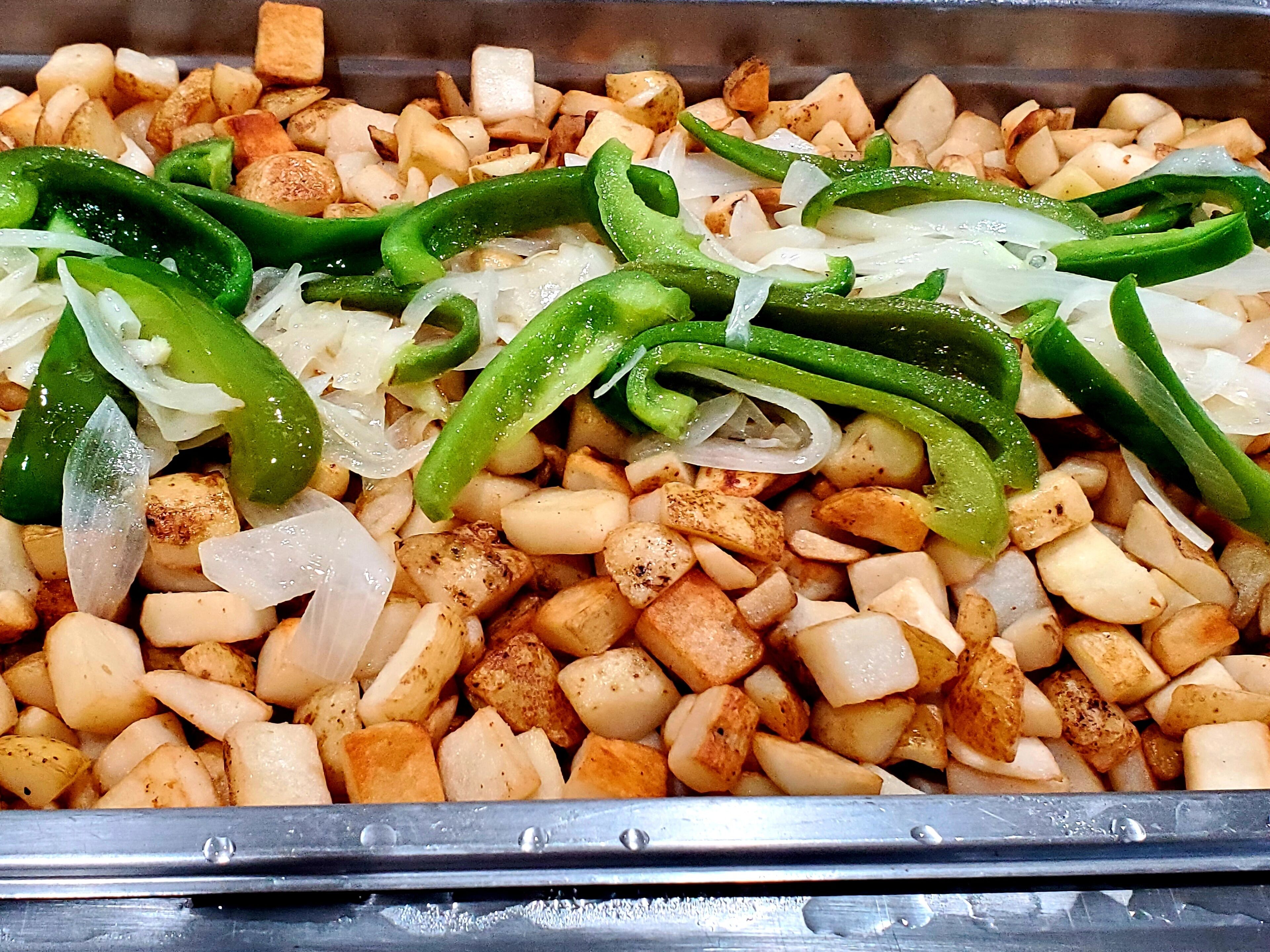 Una bandeja con papas sazonadas y pimientos verdes.