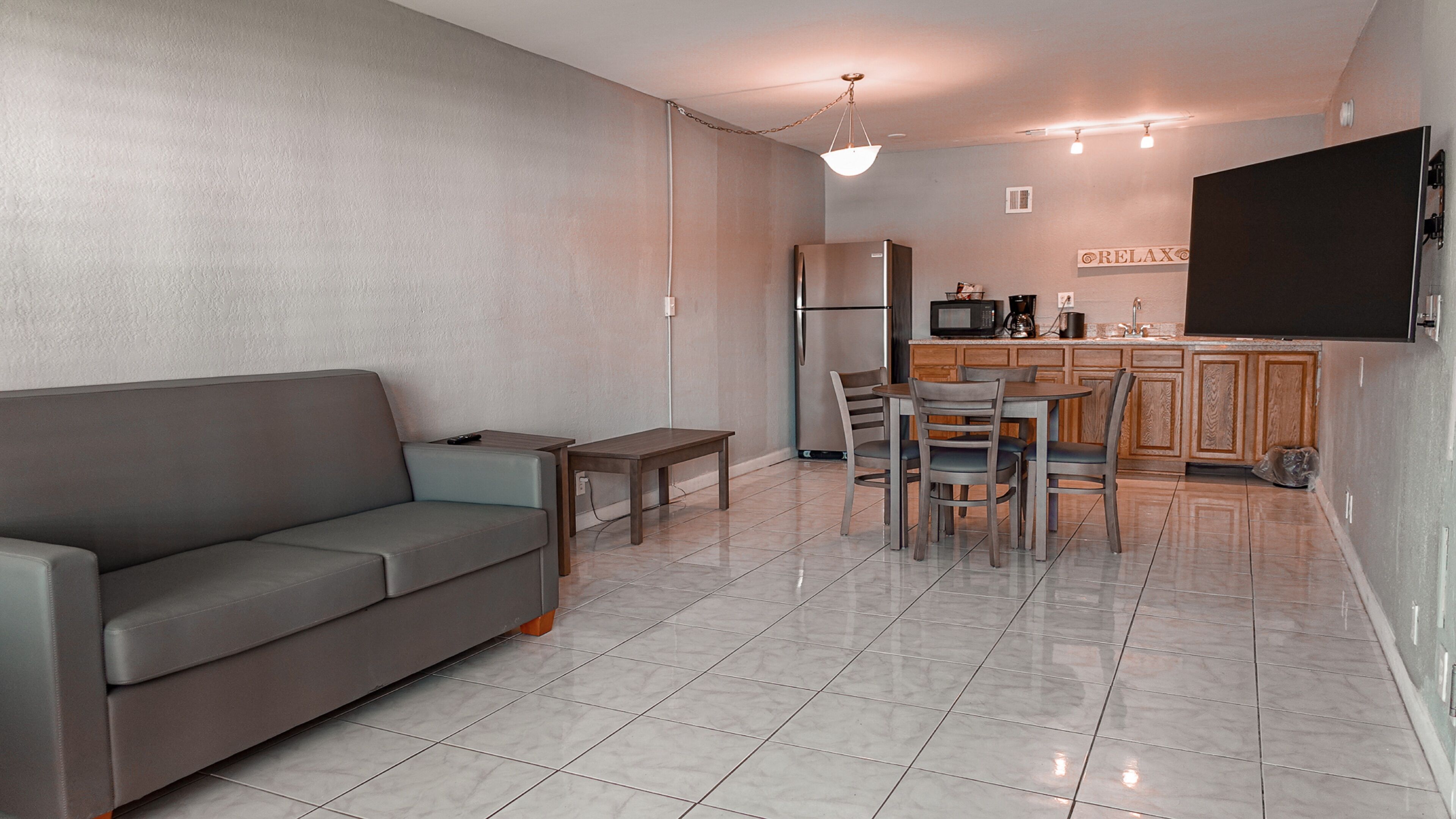 Una cocina moderna con comedor, un sofá y un televisor montado en la pared.