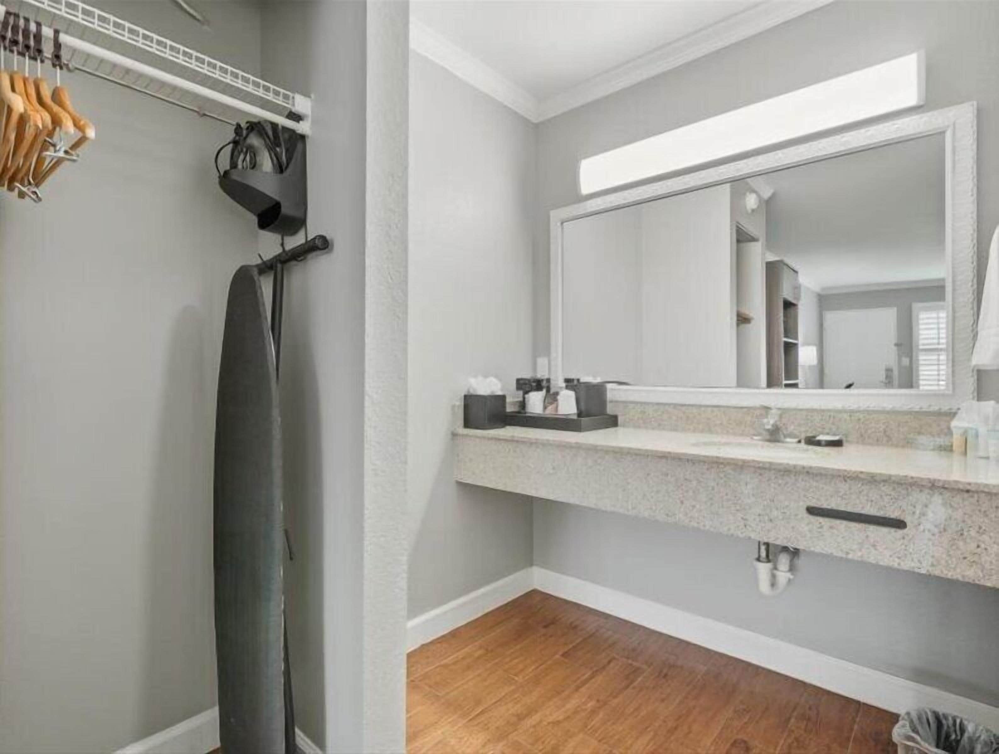 A bathroom with a large mirror, a towel rack, a shower curtain, and a countertop with toiletries.