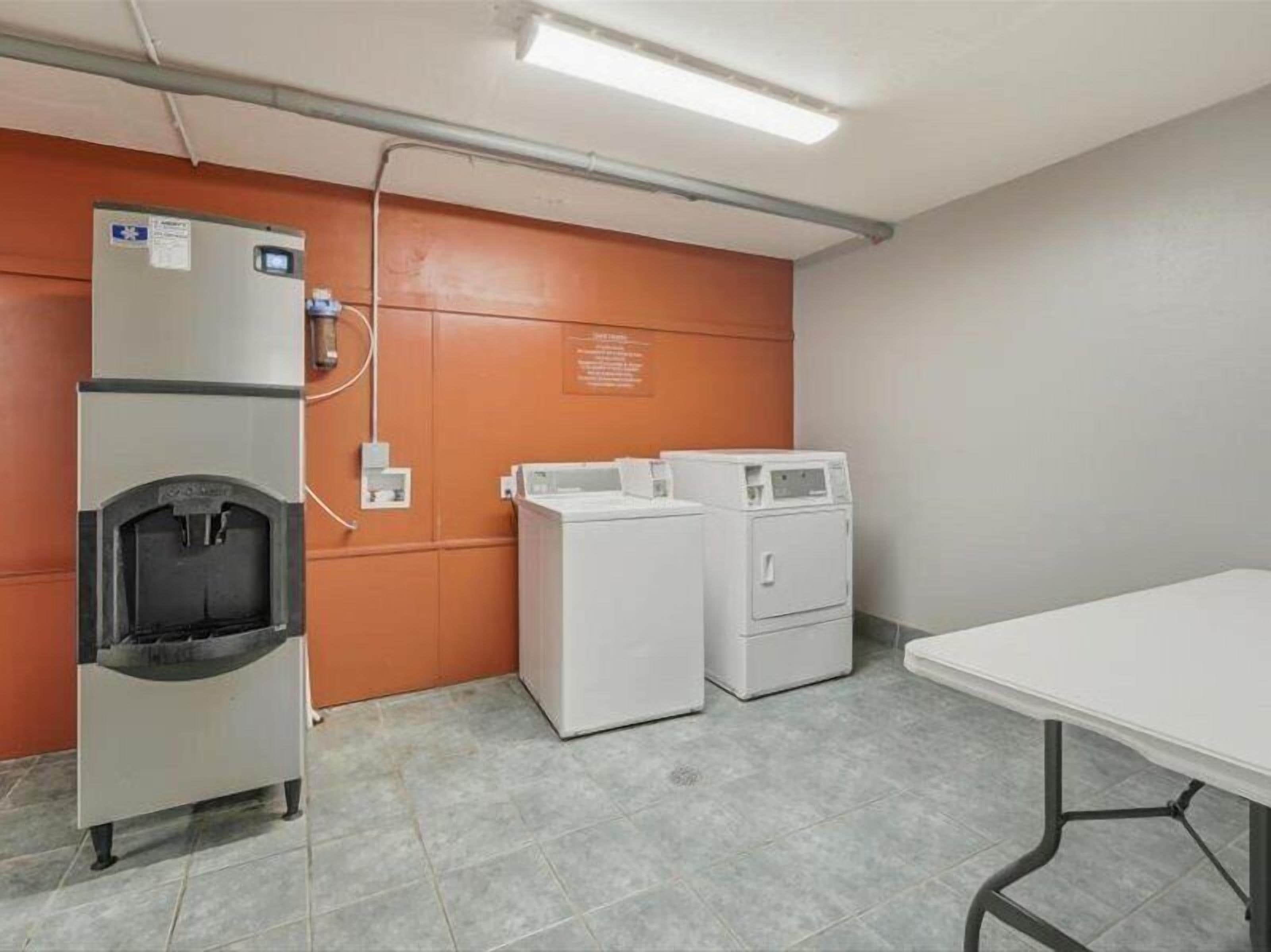 A laundry room with a water dispenser, two dryers, and a table.