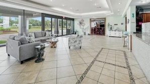 A spacious living area with a grey sofa, a coffee table, and a patterned rug. - Vero Beach Inn & Suites I-95 (Vero Beach)