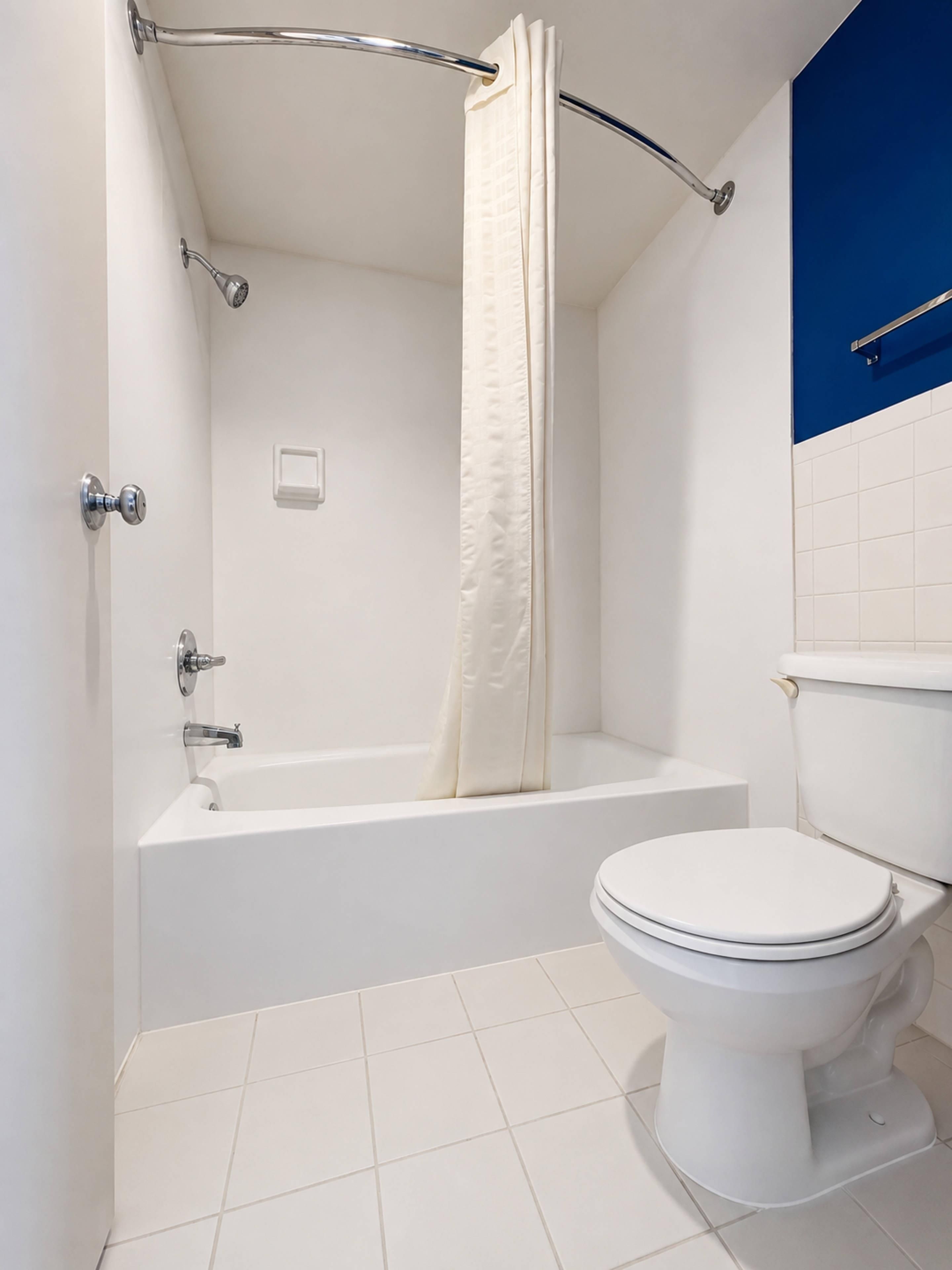 A bathroom with a bathtub, toilet, and shower curtain.