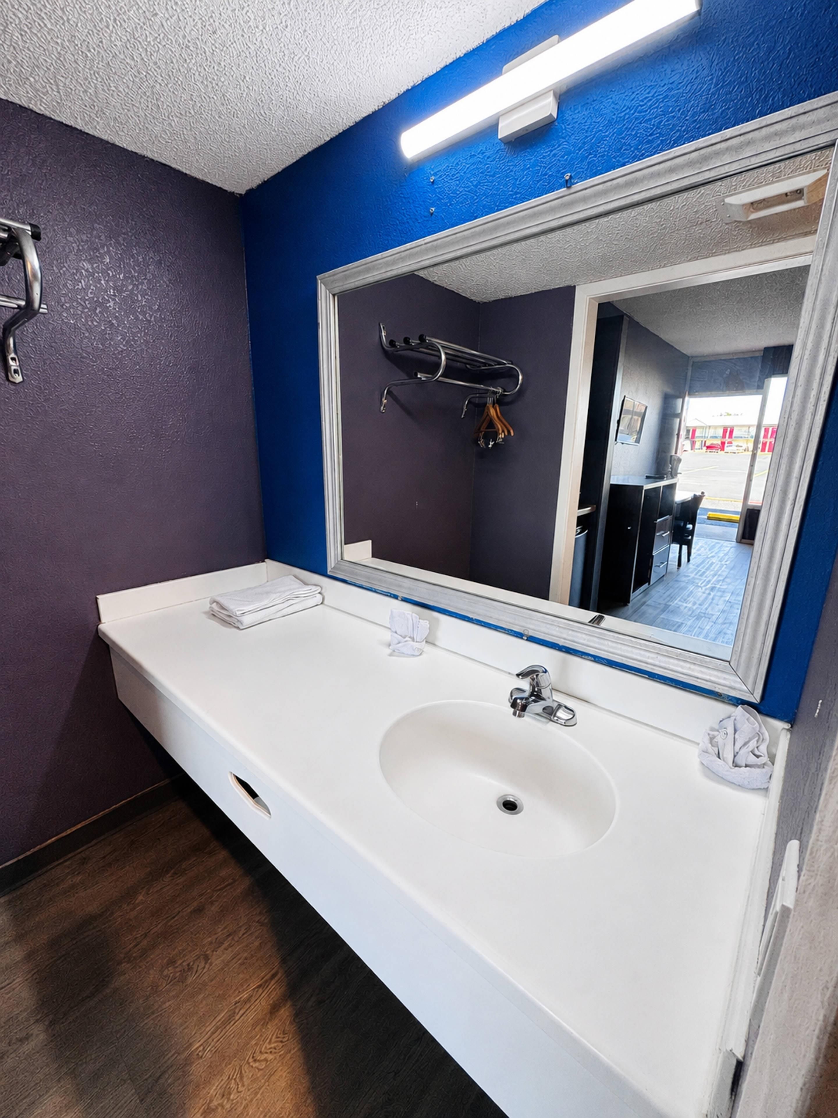 A bathroom with a white sink, a mirror, and a towel rack.