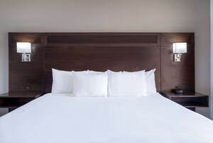 A hotel room with a large bed, two bedside tables, and two wall-mounted lamps.