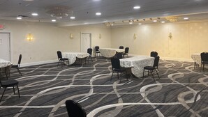 A conference room with multiple tables and chairs, carpeted flooring, and ceiling lights. - Comfort Inn Springfield (Springfield)