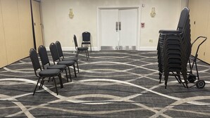A conference room with a patterned carpet, rows of chairs, a chandelier, and a door with an exit sign. - Comfort Inn Springfield (Springfield)