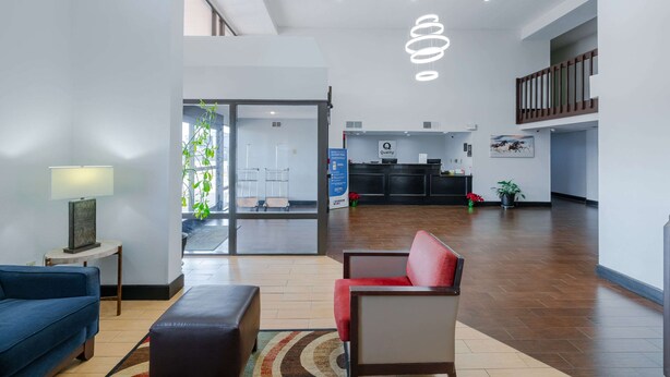 Un vestíbulo moderno con una recepción, un sofá azul, una silla roja y una escalera.