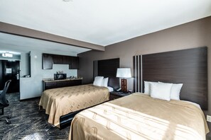 A hotel room with two beds, a desk, a chair, and a small kitchenette. - Quality Inn Olive Branch - Memphis South (Olive Branch)