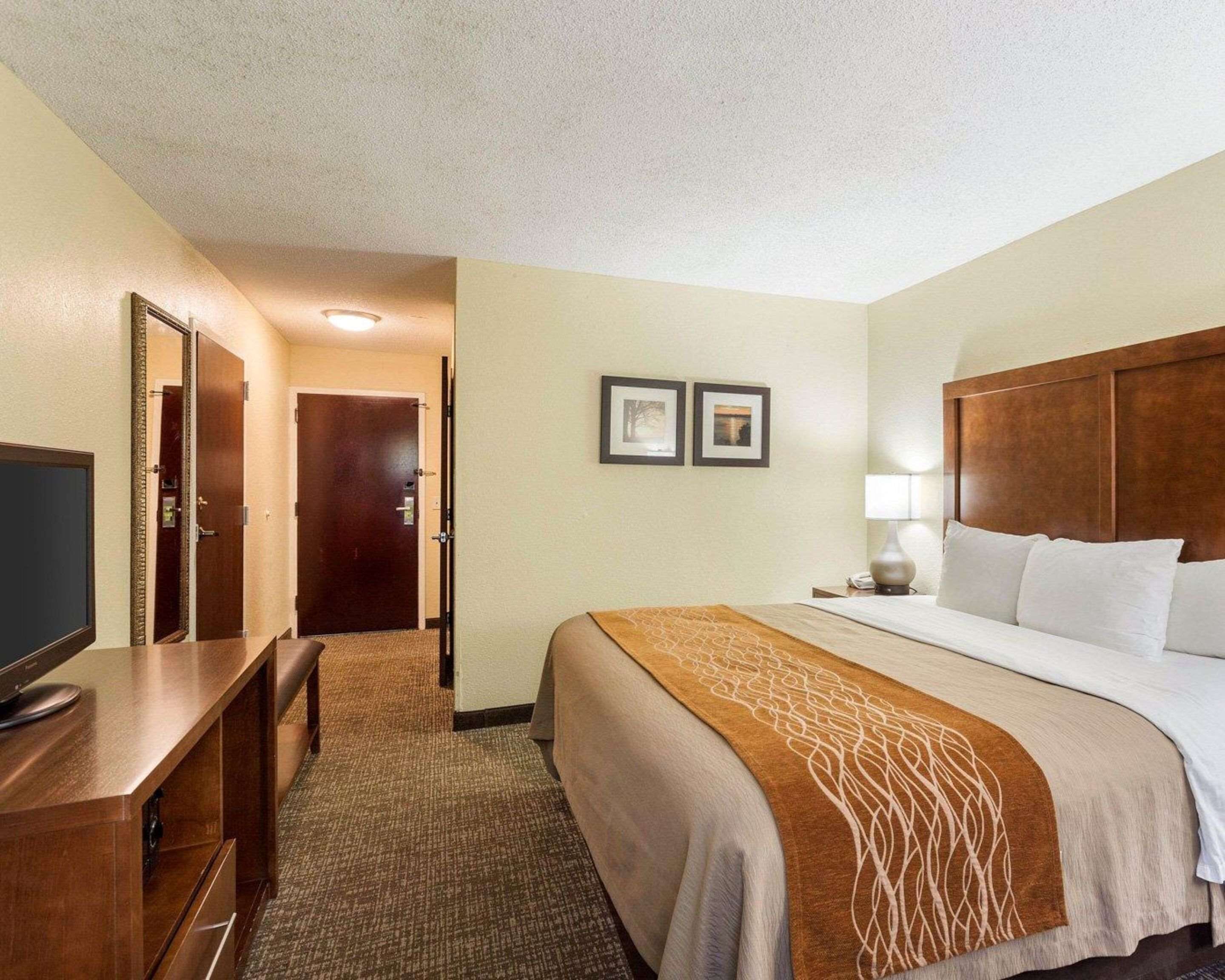 Une chambre d’hôtel avec un lit, un bureau, une télévision et un miroir.