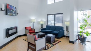 Una sala de estar moderna con un televisor de pantalla plana, un sofá azul, una silla roja y una planta en maceta.