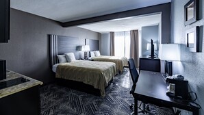 Una habitación de hotel con dos camas, un escritorio, una silla, un televisor y una lámpara.