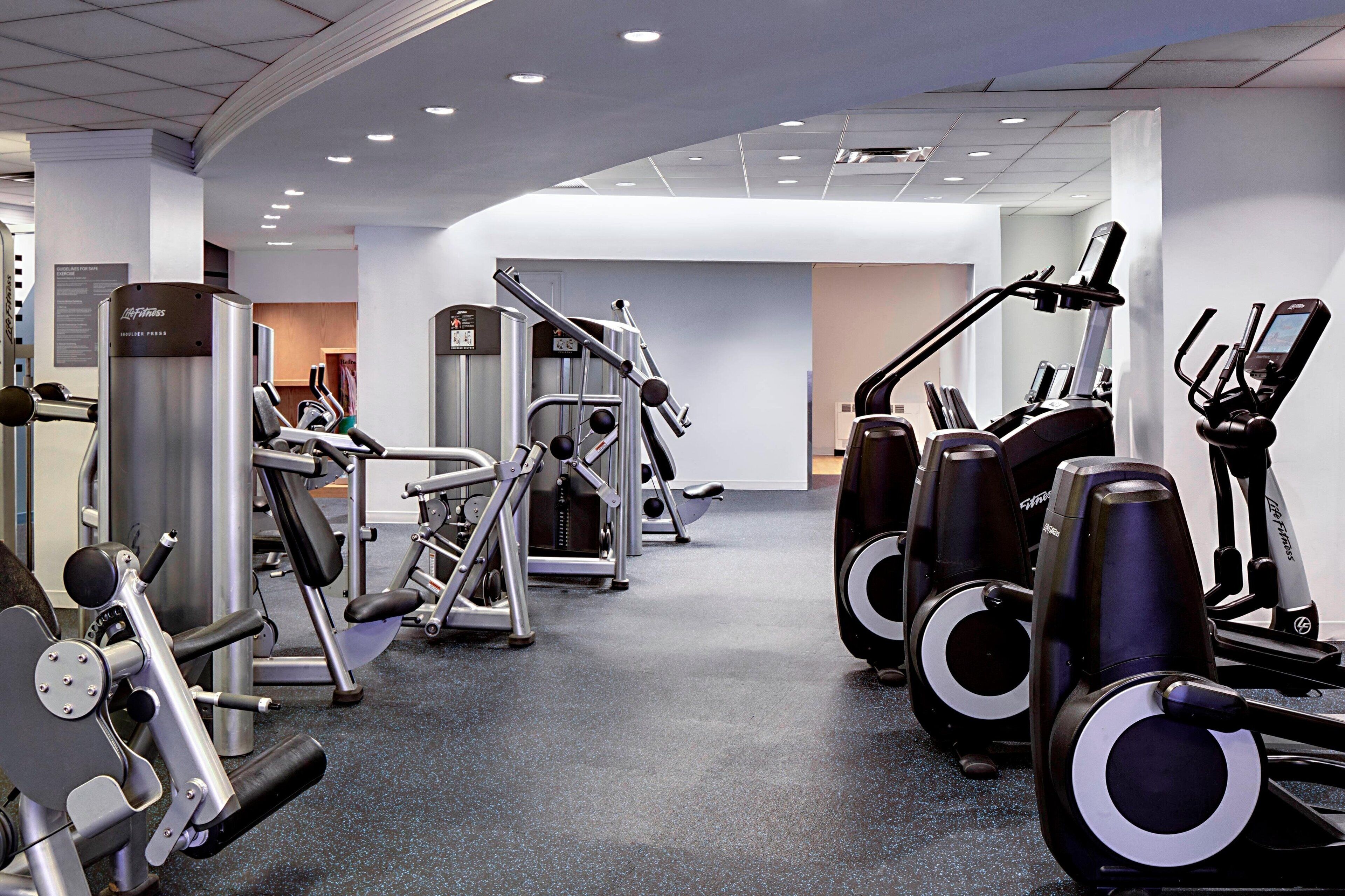 A gym with various exercise equipment including treadmills, elliptical machines, and weight machines.