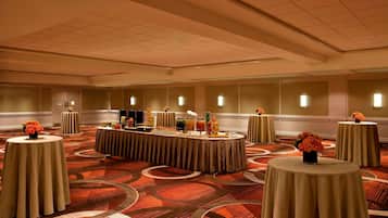 A conference room with round tables, a buffet setup, and a carpeted floor.