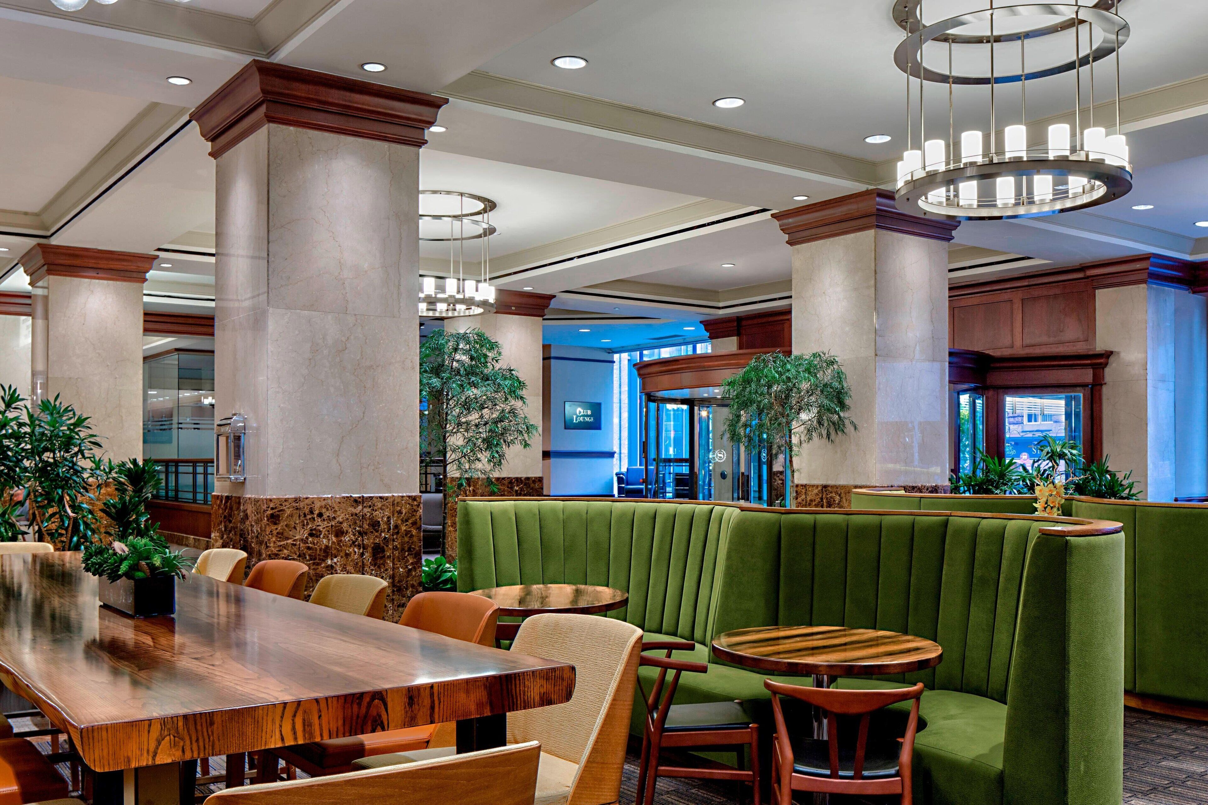 A restaurant with a green booth seating area, wooden tables, and chairs.