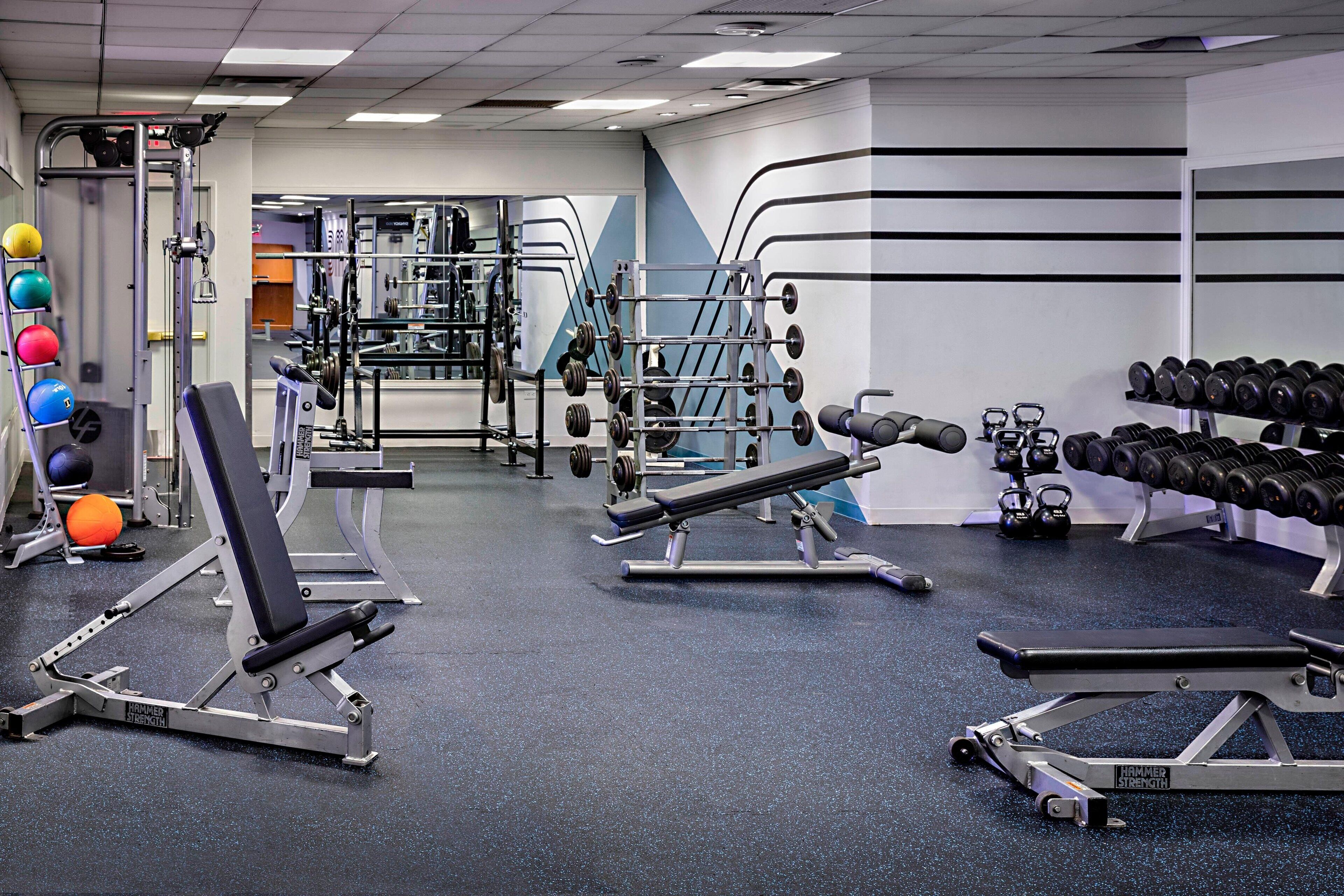 A gym with various exercise equipment, including weight machines, free weights, and cardio machines.