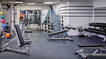 A gym with various exercise equipment, including weight machines, free weights, and cardio machines.