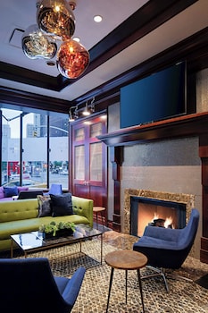 A hotel room with two beds, a desk with a chair, a TV, and a view of a cityscape at night. at Sheraton New York Times Square Hotel