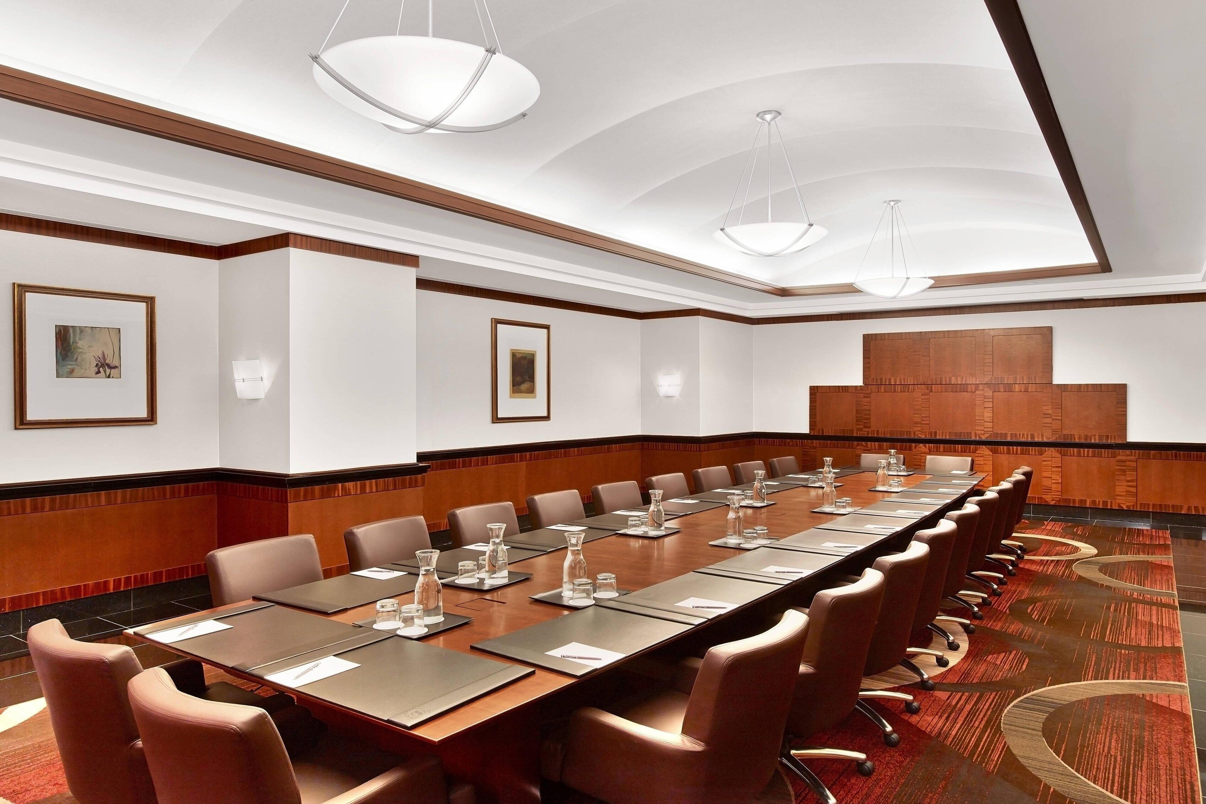 A conference room with a long table, multiple chairs, and framed artwork on the walls.