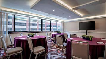 A conference room with round tables, chairs, and a large window with a city view.