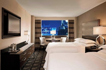 A spacious lobby with marble flooring, large columns, and a cityscape view through a large window. at Sheraton New York Times Square Hotel