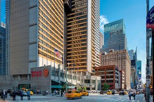A busy urban street with tall buildings, including a Sheraton New York hotel.
