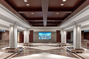 A lobby with marble columns, a green reception desk, and a large chandelier. at Sheraton New York Times Square Hotel
