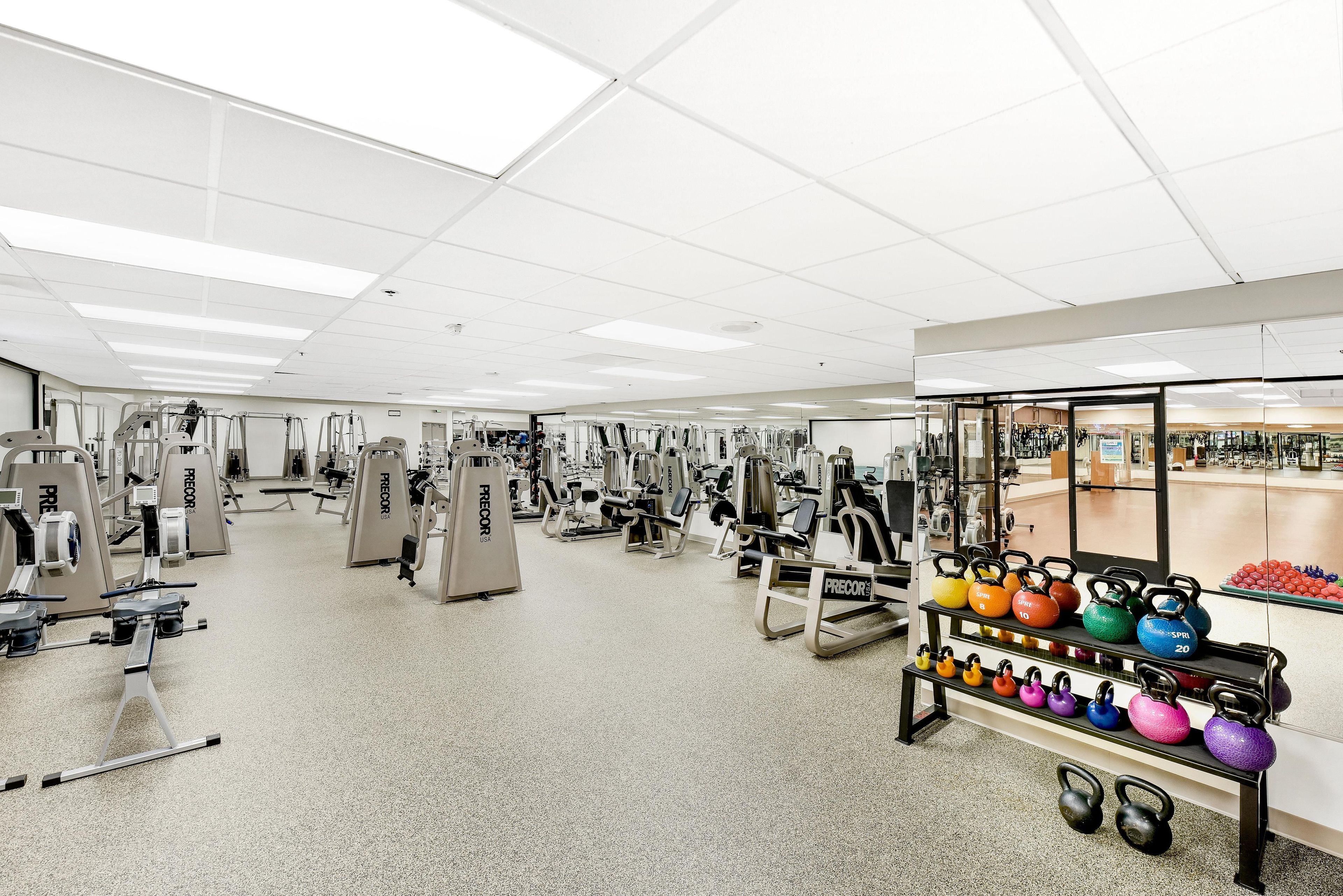 Un gimnasio con diversos equipos de ejercicio y pesas rusas.