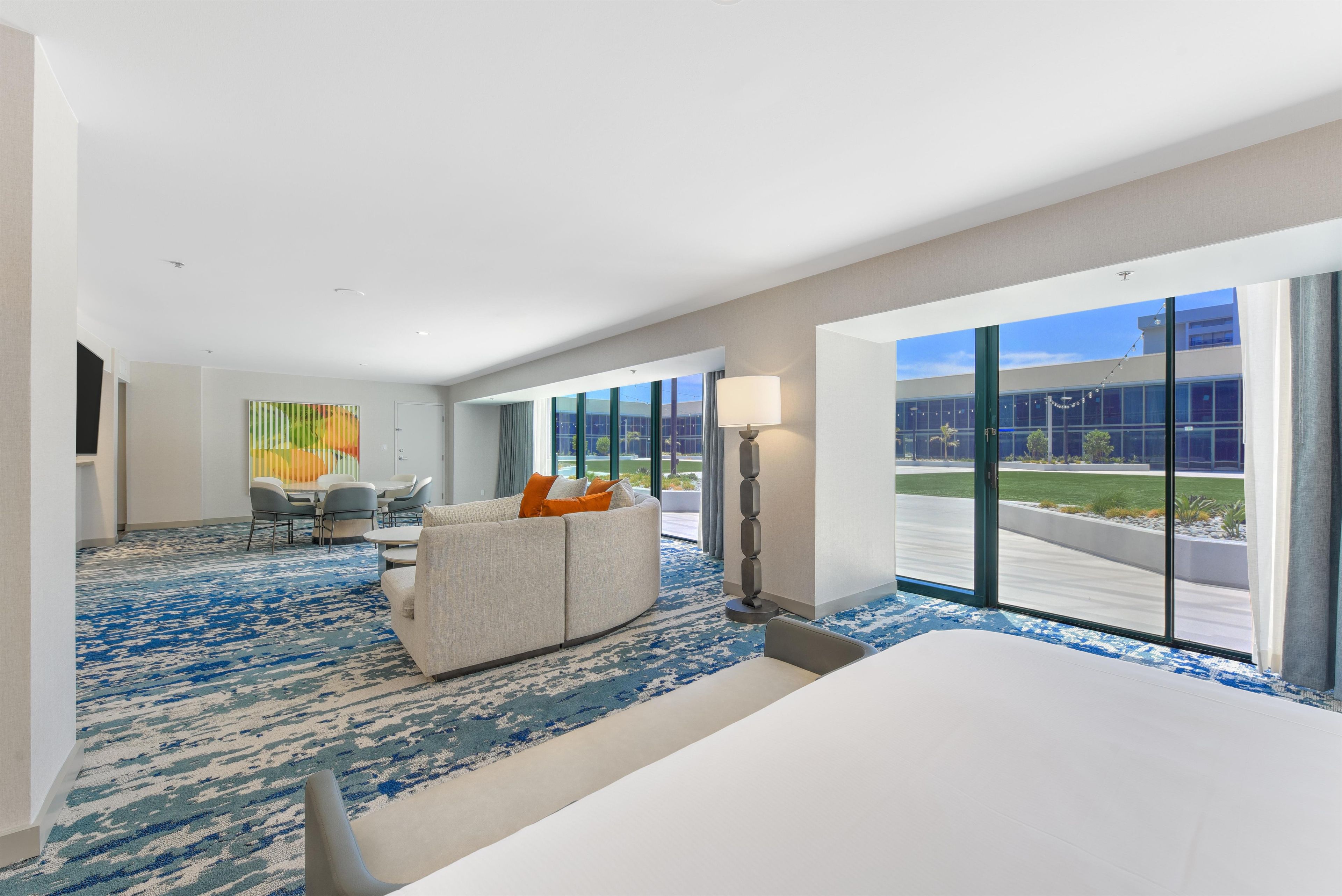 Une chambre d’hôtel avec un grand lit, un canapé, une table à manger avec des chaises et une vue sur l’extérieur.