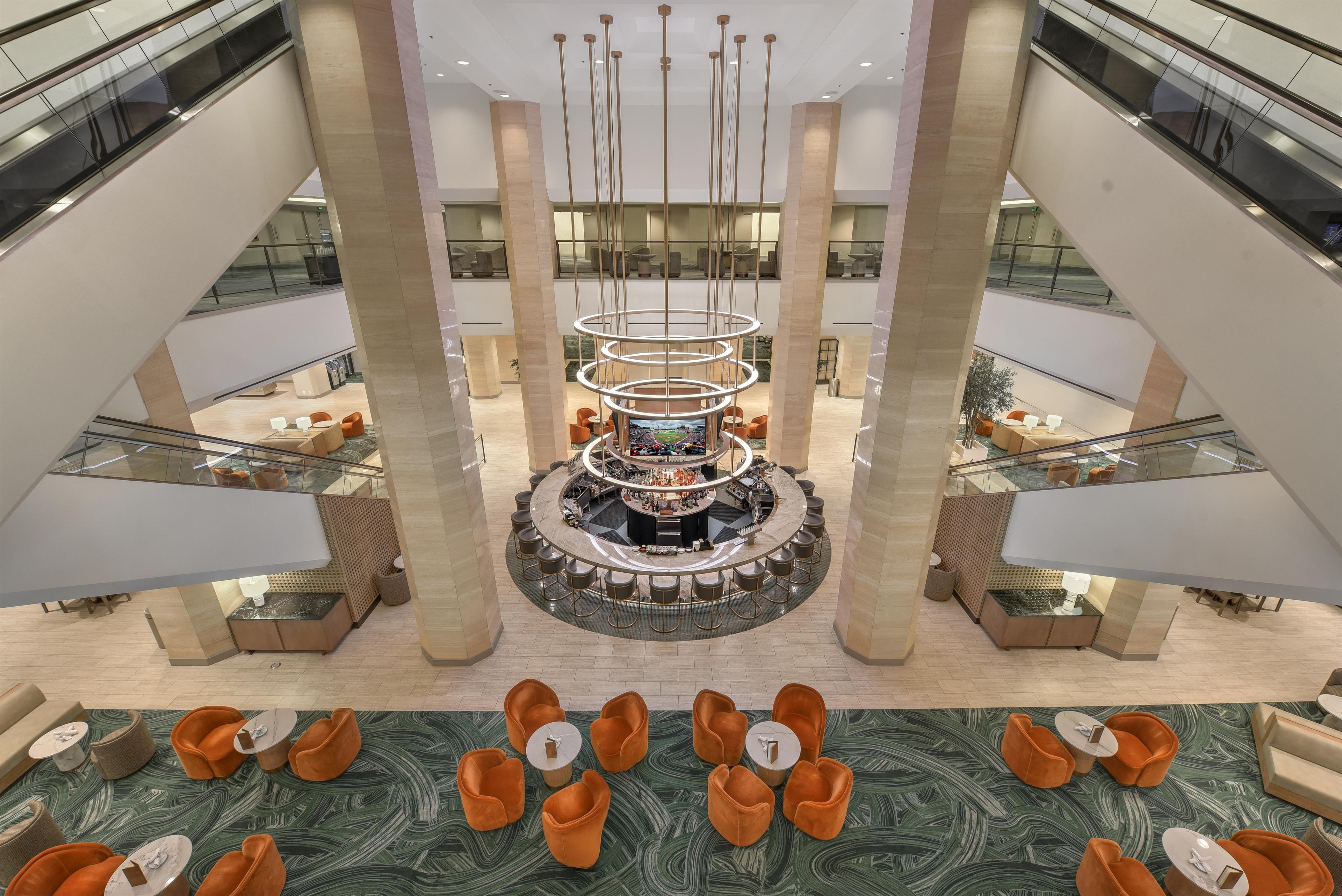 A multi-level atrium with a central bar area, seating arrangements, and a modern chandelier.