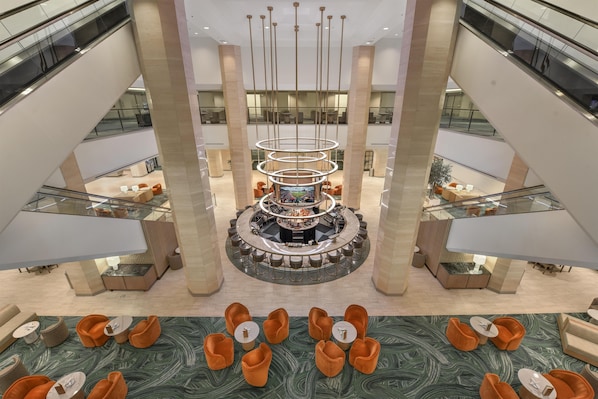 A multi-level atrium with a central bar area, seating arrangements, and a modern chandelier. - Hilton Anaheim (Anaheim)