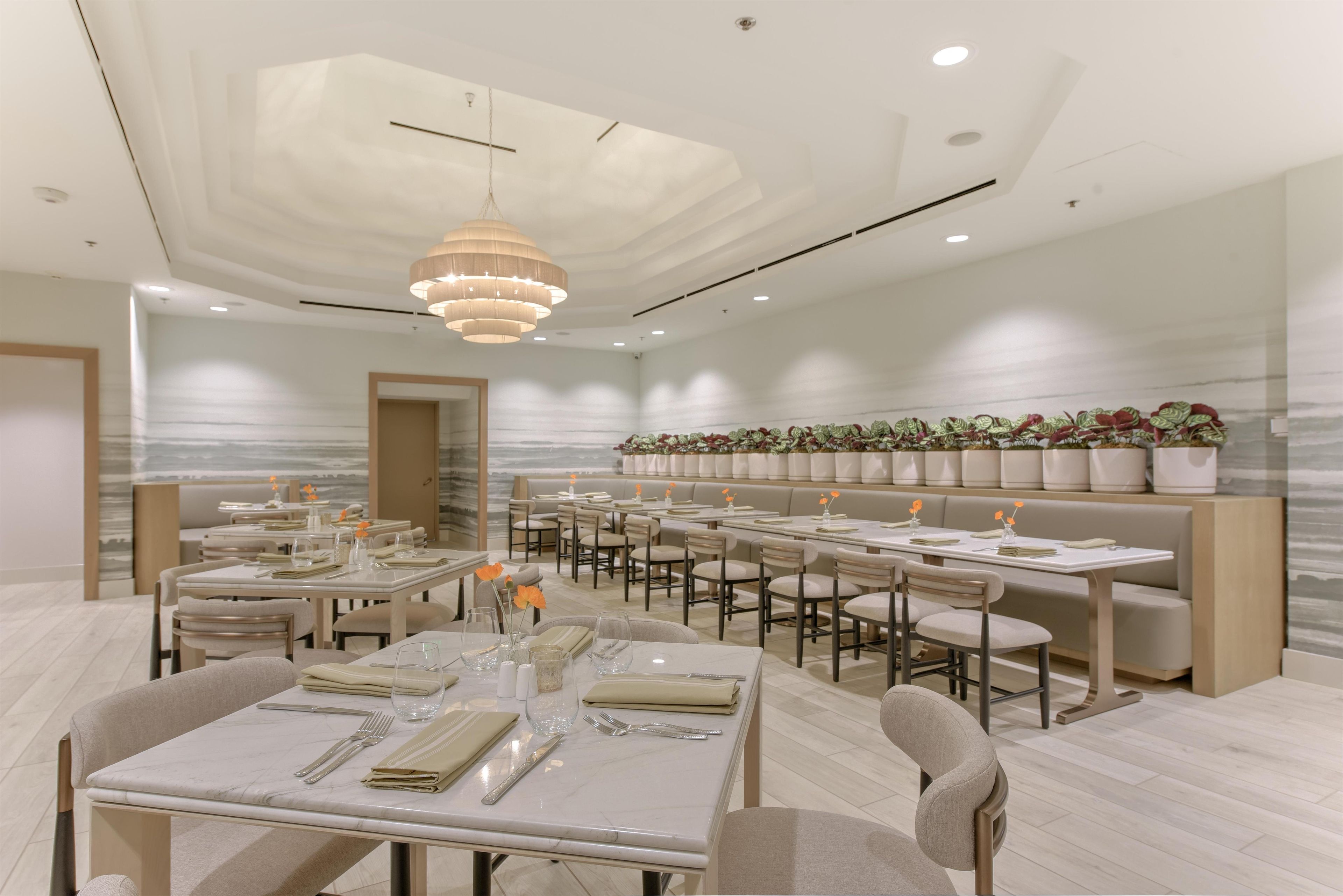 Un interior de restaurante moderno con varias mesas, sillas y una lámpara central.