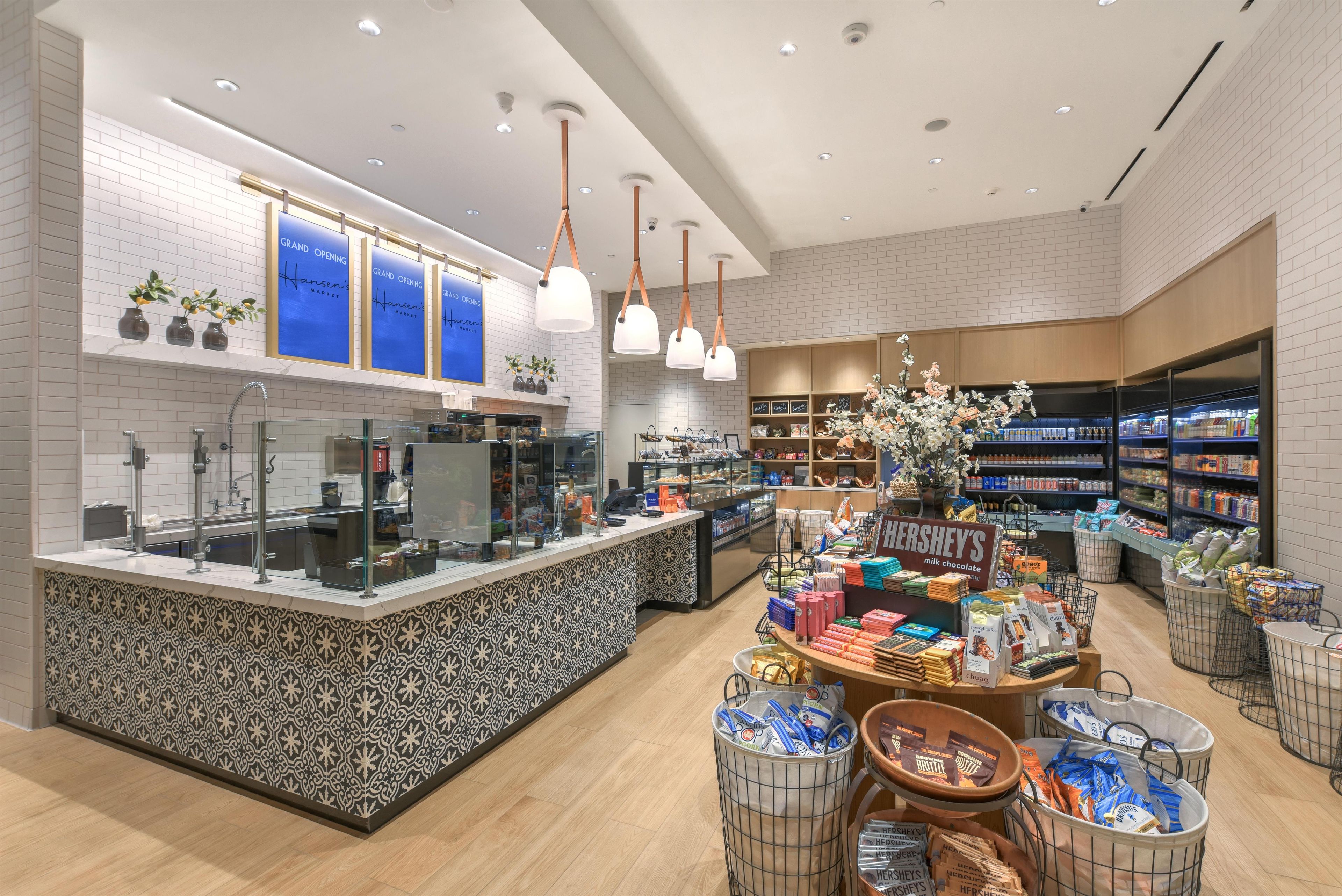 A modern retail store interior with a central counter, shelves stocked with products, and hanging pendant lights.