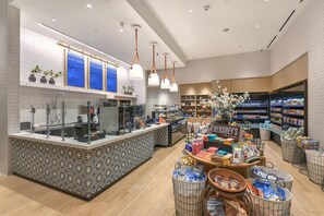 L’intérieur d’un magasin moderne se caractérise par un comptoir central, des étagères remplies de produits et des luminaires suspendus.