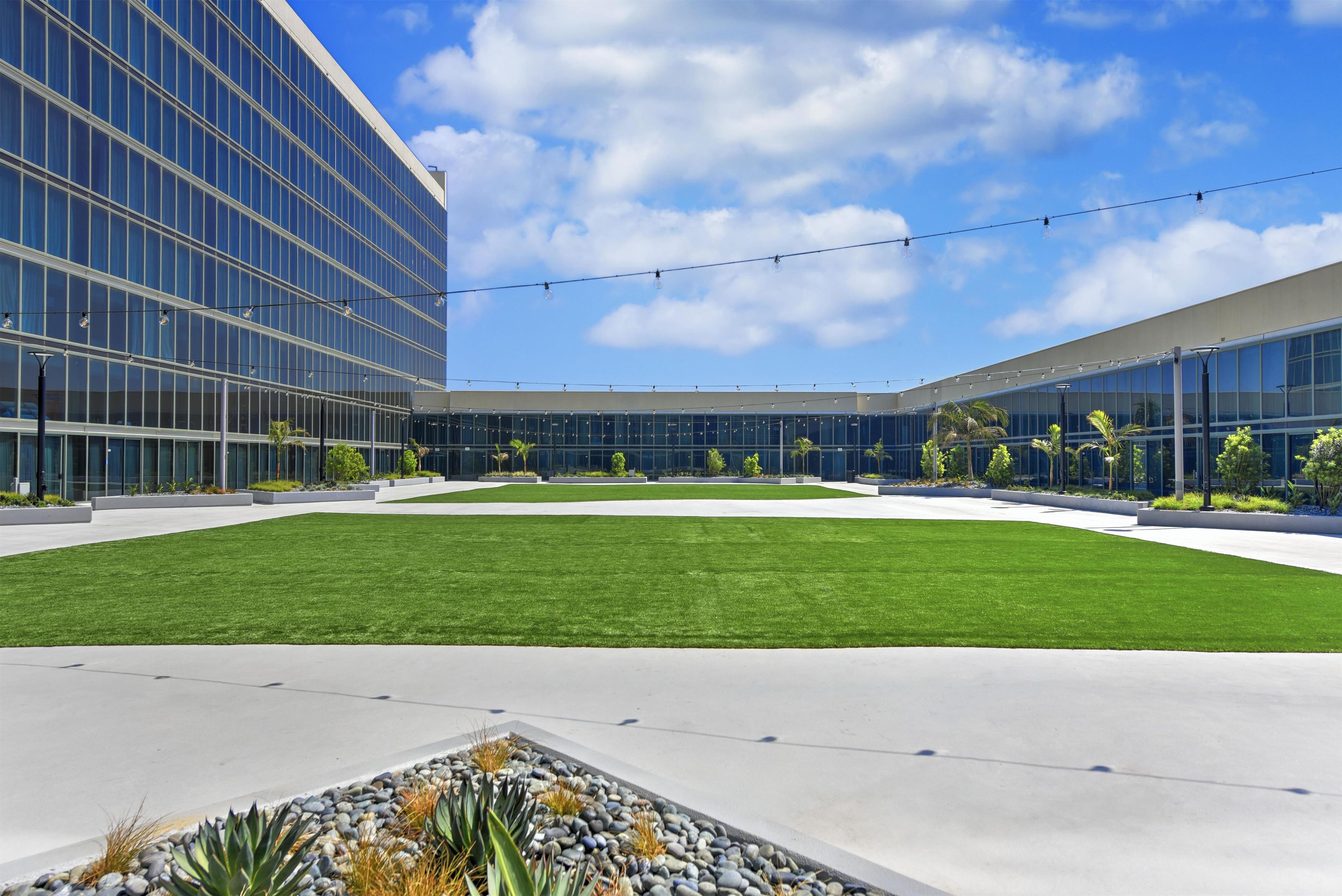 A modern building with a central courtyard, surrounded by glass windows and a well-maintained lawn.
