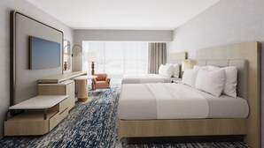 A hotel room with a large bed, a desk with a chair, a TV, and a window with curtains.
