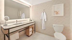A modern bathroom with a large mirror, a sink, a toilet, and a towel rack.