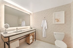 A modern bathroom with a large mirror, a sink, a toilet, and a towel rack. - Hilton Anaheim (Anaheim)